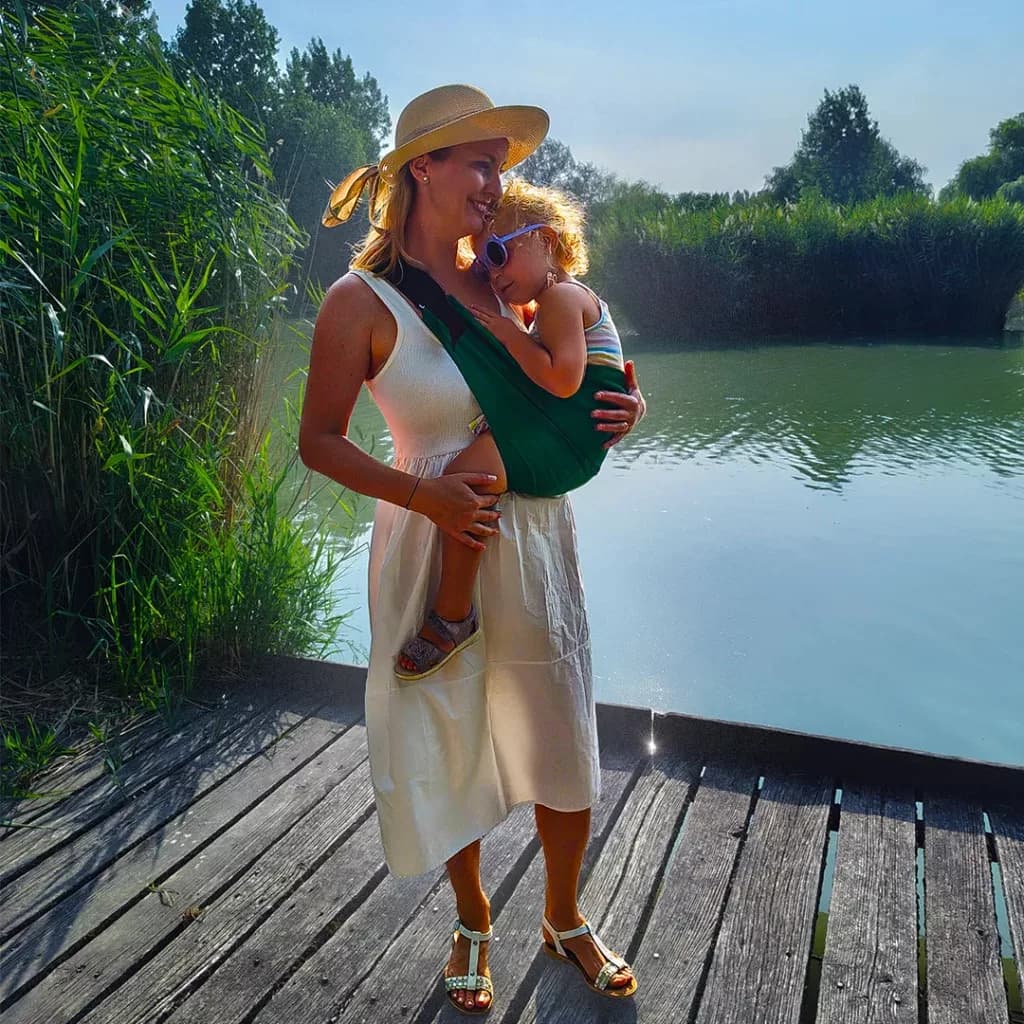 Mutter trägt ein Kind am See